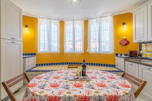A dining area with a round table, chairs, a bottle, and a tray with food items. - Apartment 'Magnolia' with Pool, Wi-Fi and Air Conditioning (Arenella)