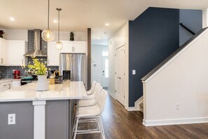 A modern kitchen with a central island, stainless steel appliances, and pendant lighting. - Brand-New 2026 Home • Near Downtown (Indianapolis)