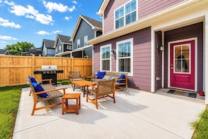 A residential backyard with a patio, outdoor furniture, a grill, and a wooden fence. - Brand-New 2026 Home • Near Downtown (Indianapolis)