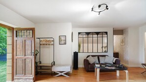A spacious living area with a wooden floor, a sofa, a coffee table, and a door with a decorative panel.