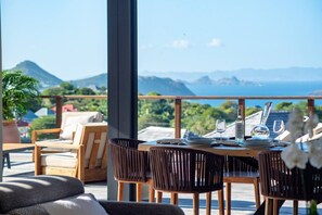 A dining area with a table set for two, overlooking a mountainous landscape. - Sweet Hill - Villa Kaye (Gustavia)