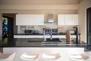 A modern kitchen with white cabinets, a stainless steel sink, and a black countertop. - Sweet Hill - Villa Kaye (Gustavia)
