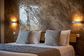 A bed with a headboard, two wall-mounted lights, and a textured wall behind the bed.
