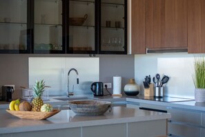 A modern kitchen with a central island, a built-in sink, and a variety of kitchen utensils and appliances. - Sweet Hill - Villa CALI (Saint-Barthelemy)