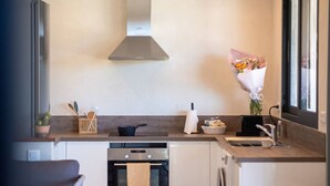 A compact kitchen with a stove, oven, and sink. There is a window with a view of the outside.