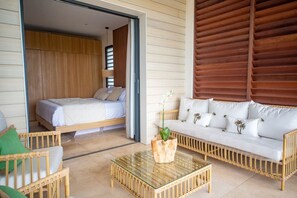 A room with a bed, a sofa, a glass coffee table, and wicker furniture. - Sweet Hill - Villa Rosa (Petite Saline)