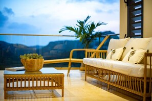 A balcony with a wicker sofa, a small table, and a potted plant. - Sweet Hill - Villa Rosa (Petite Saline)
