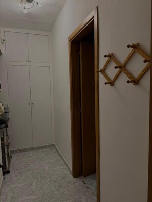 Un couloir avec une armoire, une porte en bois et un porte-manteau fixé au mur.