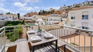 A balcony with a table set for dining, overlooking a residential area with houses and a clear sky. - Villa Oasis del Sol II – Pool – Sea Views (Urbanización Cerro Garbancito)