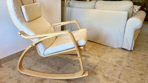 En moderne stue med en vippestol, en sofa og en gulvlampe.