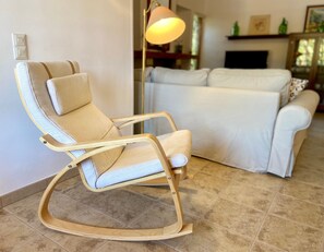 A modern living room with a rocking chair, a sofa, and a floor lamp. - Charming rustic home in Alaró, perfect for families and groups amid nature (Alaró)