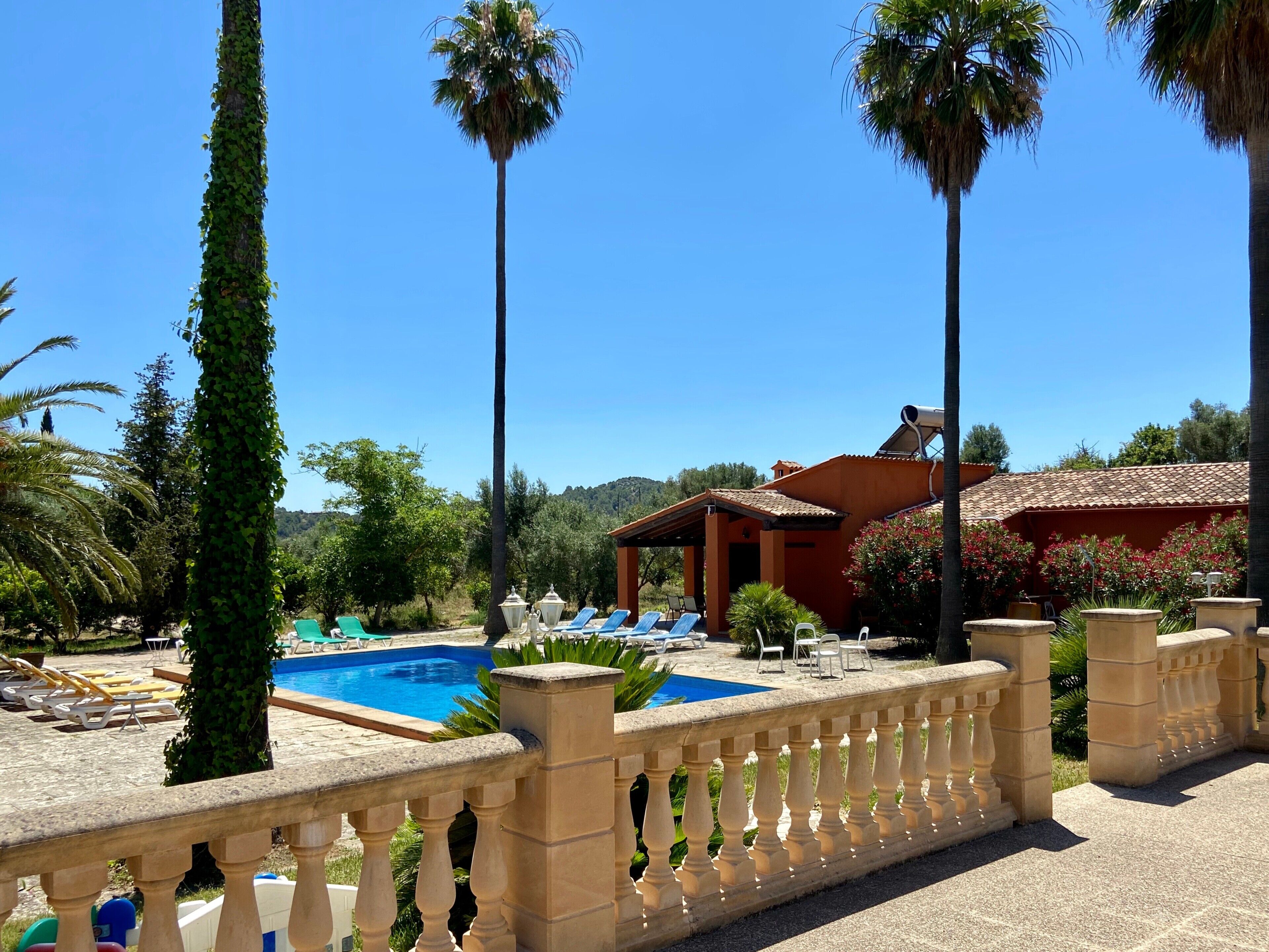 Ein Poolbereich mit Liegestühlen, einer Steinbalustrade und einem Gebäude mit einem Ziegeldach.. Charmantes, rustikales Haus in Alaró – ideal für Familien & Gruppen inmitten der Natur