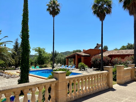 Ein Poolbereich mit Liegestühlen, einer Steinbalustrade und einem Gebäude mit einem Ziegeldach.. Charmantes, rustikales Haus in Alaró – ideal für Familien & Gruppen inmitten der Natur
