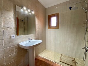 Ein Badezimmer mit Waschbecken, Spiegel, Dusche und einem kleinen Fenster.