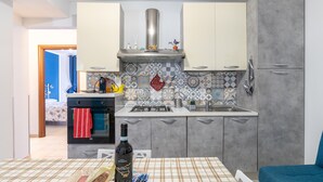 A modern kitchen with grey cabinets, a stainless steel range hood, and a tiled backsplash. - Apartment 'Milu' Poolside, Wi-Fi and Air Conditioning (Arenella)