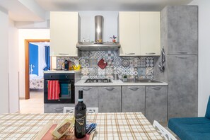 Eine moderne Küche mit grauen Schränken, einer Edelstahl-Dunstabzugshaube und einer gefliesten Spritzschutzwand.