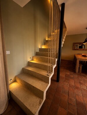 Eine Holztreppe mit schwarzer Handlauf und Wandleuchten.