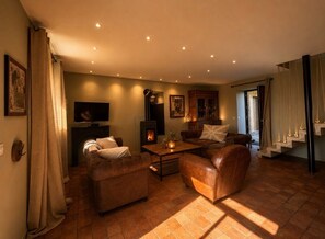 Ein gemütliches Wohnzimmer mit Kamin, Ledersofas, einem Flachbildfernseher und einer Treppe.