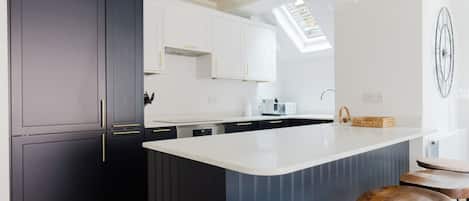 A modern kitchen with dark cabinetry, a large island, and bar stools.