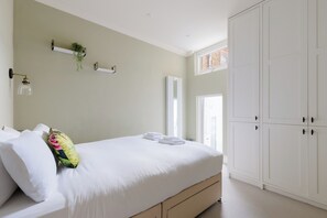 Ein Schlafzimmer mit Bett, Kleiderschrank, Heizkörper und Fenster.