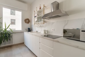 A modern kitchen with white cabinetry, a built-in microwave, and a window with a view of buildings. - Spacious 100m2 apartment, ideal for up to 6 guests, located on the second floor with lift.Located in the Guastalla district, it is about a 15-minute walk from the M3 Crocetta, M4 Sforza-Policlinico and M1/M4 San Babila metro stops, with numerous surface  (Milan)