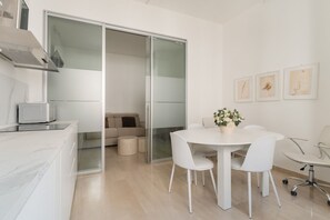A modern kitchen with a microwave, a white dining table with chairs, and a glass door leading to a living area. - Spacious 100m2 apartment, ideal for up to 6 guests, located on the second floor with lift.Located in the Guastalla district, it is about a 15-minute walk from the M3 Crocetta, M4 Sforza-Policlinico and M1/M4 San Babila metro stops, with numerous surface  (Milan)