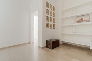 A room with a wooden floor, white walls, a door, a shelf with vases, and framed pictures on the wall. - Spacious 100m2 apartment, ideal for up to 6 guests, located on the second floor with lift.Located in the Guastalla district, it is about a 15-minute walk from the M3 Crocetta, M4 Sforza-Policlinico and M1/M4 San Babila metro stops, with numerous surface  (Milan)