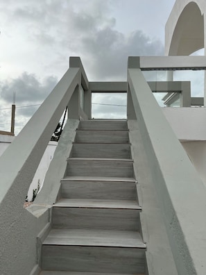 Eine Treppe führt zu einem Balkon mit Blick auf den Himmel und Wolken.