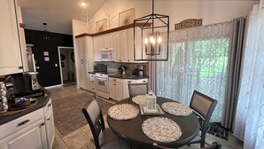 A modern kitchen with white cabinets, a dining table with placemats, and a chandelier. - Spacious, 9-bed double house in peaceful setting, 12 miles from Frankenmuth (Clio)