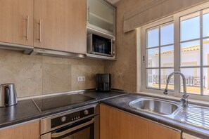 A kitchen with a microwave, stove, oven, and sink. - #318 Spacious 2BR Apartment | Bright Interiors (Albufeira)