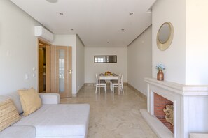 A modern living room with a sofa, a dining table with chairs, a fireplace, and a mirror on the wall. - #318 Spacious 2BR Apartment | Bright Interiors (Albufeira)