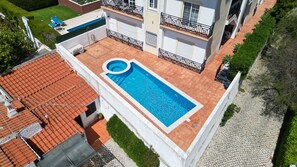 Une piscine sur le toit, avec un petit jacuzzi, le tout entouré d’un bâtiment blanc doté de balcons.