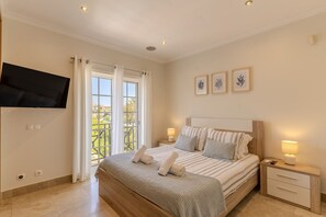 Une chambre avec un lit, des tables de chevet, une télévision et un balcon avec vue.