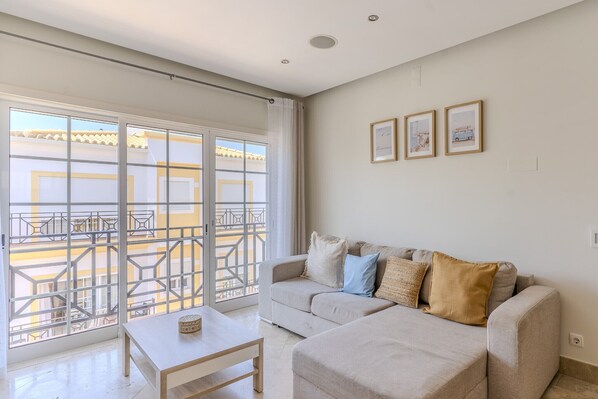 Un salon avec un canapé, une table basse et un balcon doté d’une rambarde.