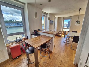 Eine moderne Küche mit großen Fenstern, einem Holzesstisch und Meerblick.