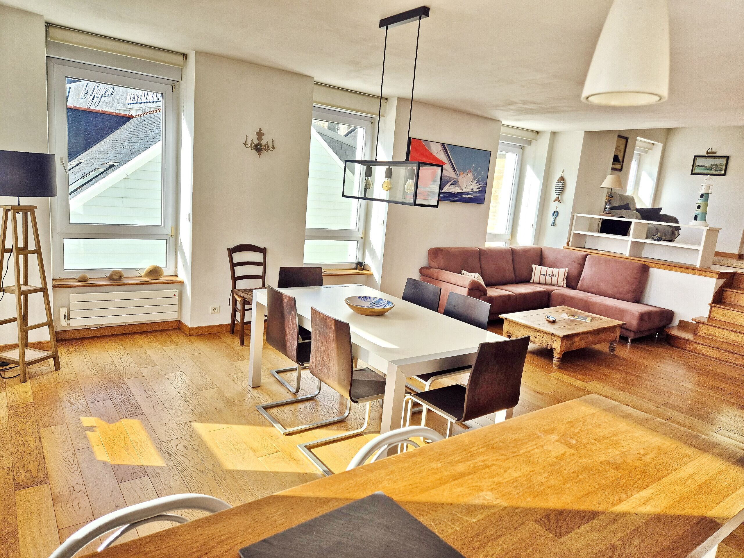 A modern living room with a dining area, a sofa, a coffee table, and a view of a building outside.