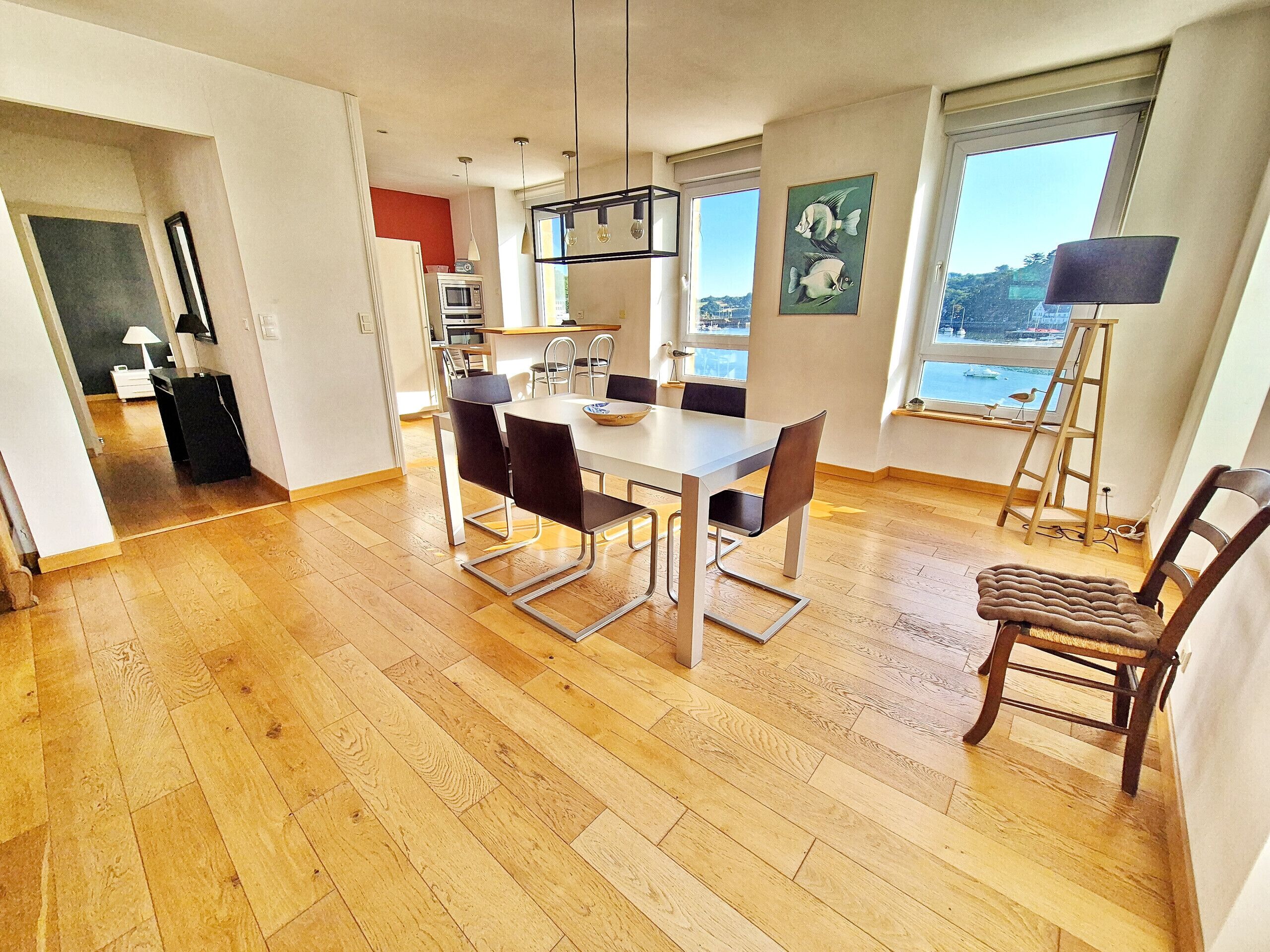 Ein zeitgemäßer Essbereich mit Holzboden, einem weißen Tisch und schwarzen Stühlen.