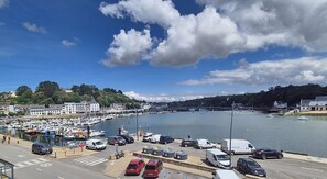 Ein Yachthafen mit vertäuten Booten, ein Parkplatz mit Autos und Gebäude entlang der Uferlinie.