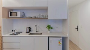 Cocina compacta con microondas, hervidor, pileta y una pequeña planta en maceta.