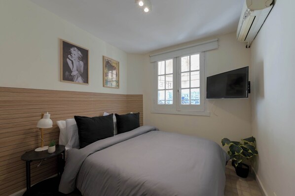 A bedroom with a bed, a nightstand, a lamp, a TV, and a window. - LDV Aparts 3CEntrepiso by MOT Rentals (Buenos Aires)