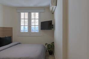 A bedroom with a bed, a window, a wall-mounted TV, and an air conditioner. - LDV Aparts 3CEntrepiso by MOT Rentals (Buenos Aires)