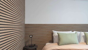 Quarto com cama, almofadas, mesa de cabeceira e abajur.