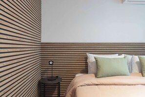 Ein Schlafzimmer mit einem Bett, Kissen, einem Nachttisch und einer Lampe.