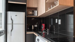 Uma cozinha compacta com geladeira, micro-ondas, cafeteira e máquina de lavar.