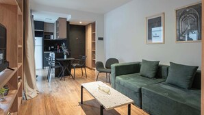 Uma sala de estar moderna com um sofá verde, uma mesa de centro e uma área de jantar com cadeiras e uma mesa.