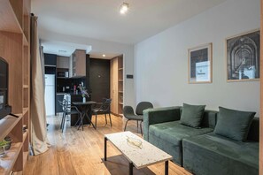 Ein modernes Wohnzimmer mit einem grünen Sofa, einem Couchtisch und einem Essbereich mit Stühlen und einem Tisch.