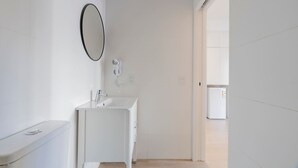 A modern bathroom with a toilet, sink, mirror, and a fan. - MOT Rentals Plaza Armenia 1A - Loft in Palermo Soho (Buenos Aires)