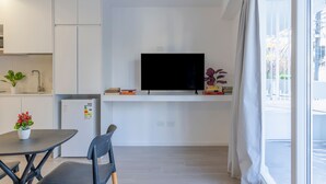 A modern kitchen with white cabinets, a built-in TV, and a dining area with a table and chairs. - MOT Rentals Plaza Armenia 1A - Loft in Palermo Soho (Buenos Aires)