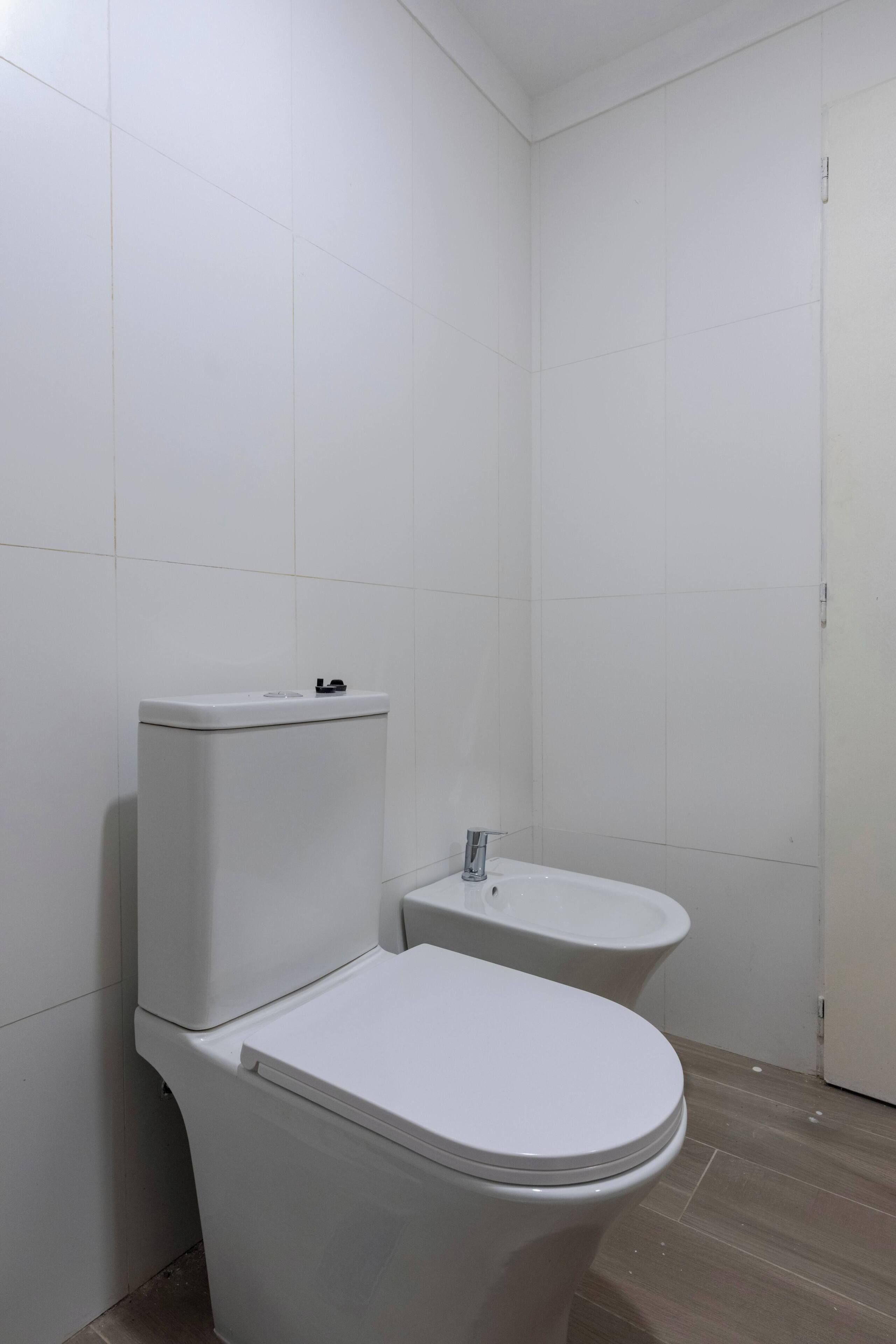 A bathroom with two toilets, a sink, and a door.