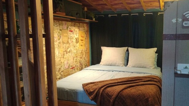 Una habitación con cama, techo de madera, pared con varios papeles y señal de Wi-Fi.